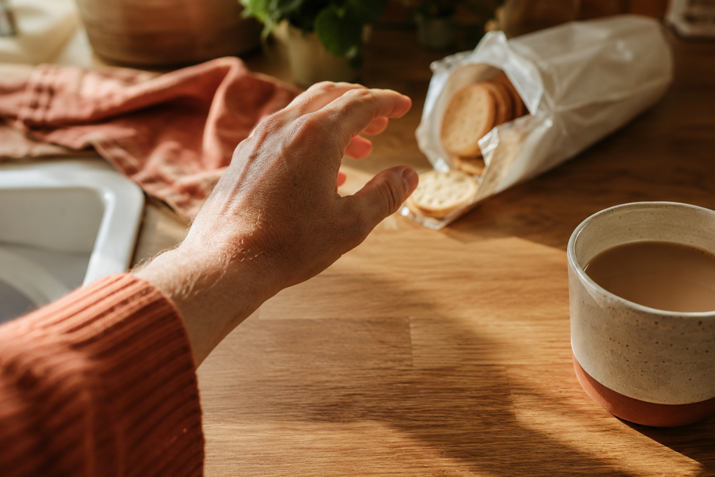Person reaching for biscuits beside a cup of tea during an everyday food craving